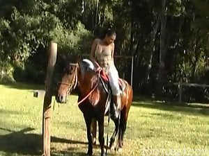 Slender rider poses fully naked on a brown stallion