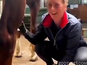 Girl in stable is happy to touch horse dick